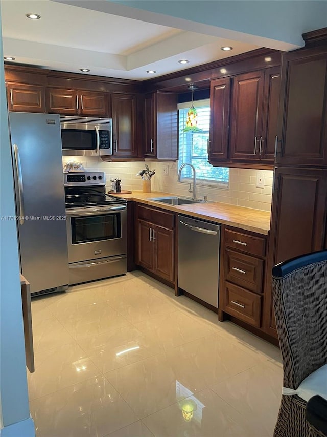 kitchen with sink, decorative light fixtures, decorative backsplash, and appliances with stainless steel finishes