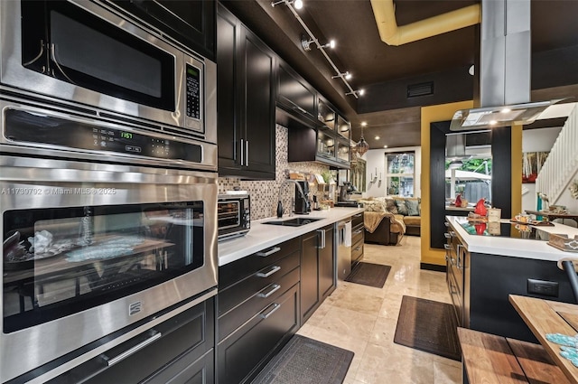 kitchen with sink, light tile patterned floors, appliances with stainless steel finishes, backsplash, and track lighting