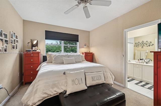 bedroom featuring connected bathroom, light colored carpet, a textured ceiling, and ceiling fan