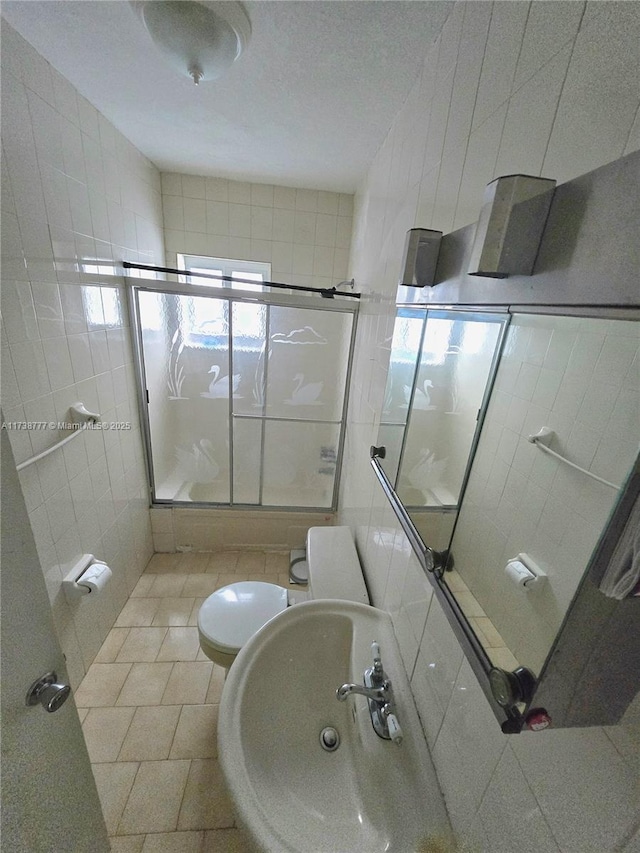 bathroom with sink, tile walls, a shower with shower door, tile patterned floors, and toilet