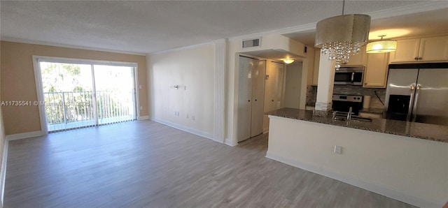 kitchen featuring stainless steel appliances, dark stone counters, light hardwood / wood-style floors, pendant lighting, and crown molding