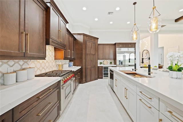 kitchen featuring sink, crown molding, white cabinetry, hanging light fixtures, and premium appliances