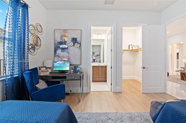 bedroom with connected bathroom, sink, and light hardwood / wood-style flooring