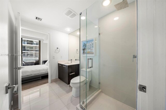 bathroom featuring tile patterned flooring, vanity, a shower with door, and toilet