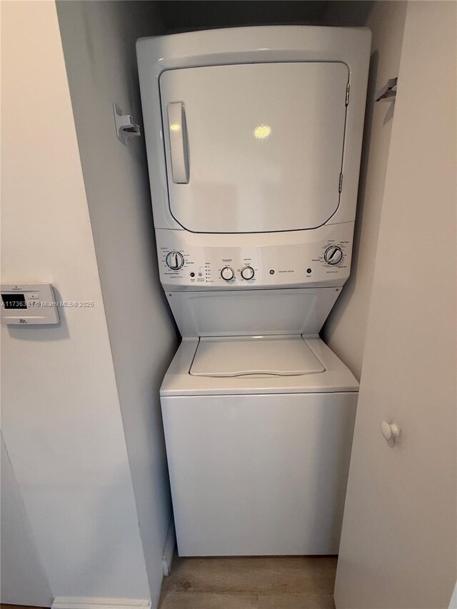 washroom featuring stacked washer and dryer and light hardwood / wood-style floors