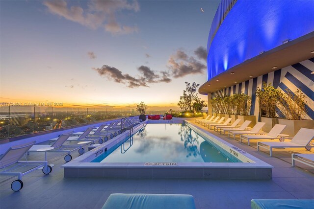 pool at dusk featuring a patio area