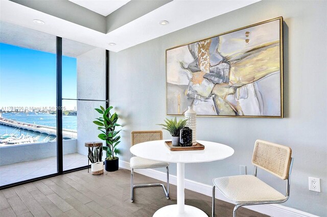 dining space with wood-type flooring, expansive windows, and a water view