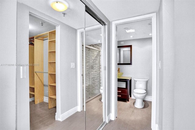 bathroom featuring wood-type flooring, toilet, and a shower