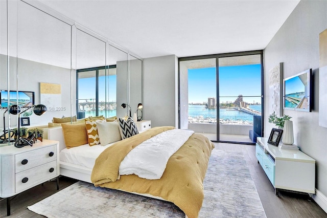 bedroom featuring dark hardwood / wood-style floors, a wall of windows, access to exterior, and multiple windows