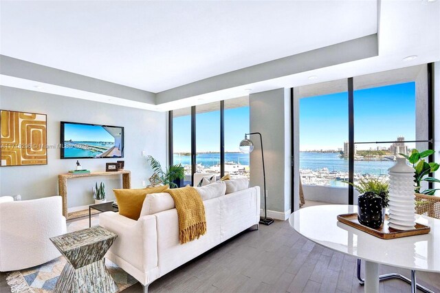 living room with a water view, hardwood / wood-style floors, and a wall of windows