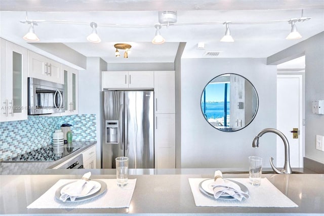 kitchen featuring stainless steel appliances, white cabinetry, sink, and backsplash