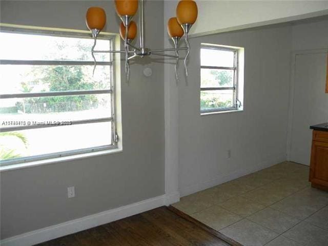 unfurnished dining area with wood-type flooring and an inviting chandelier