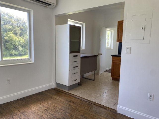 unfurnished bedroom featuring a wall mounted AC, electric panel, multiple windows, and light wood-type flooring