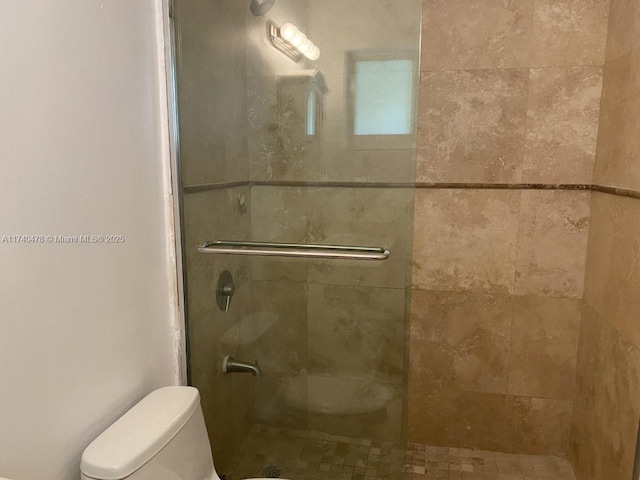 bathroom with a shower with door and toilet