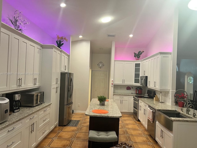 kitchen with white cabinets, light stone countertops, appliances with stainless steel finishes, and a sink