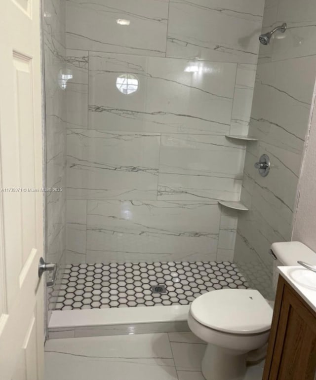 bathroom with toilet, marble finish floor, a stall shower, and vanity