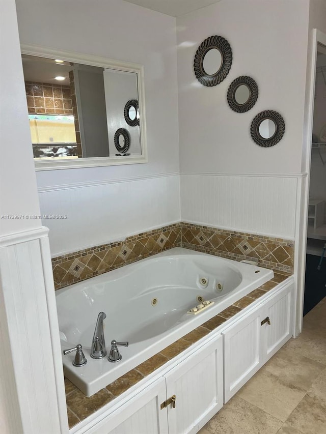 bathroom featuring a wainscoted wall and a whirlpool tub