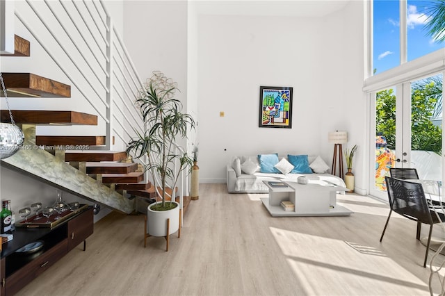 living room featuring light hardwood / wood-style floors, french doors, and a towering ceiling