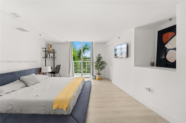 bedroom with light hardwood / wood-style flooring, access to outside, and expansive windows