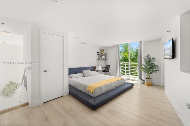 bedroom featuring light hardwood / wood-style flooring, access to outside, and expansive windows