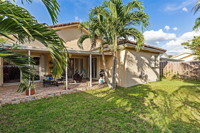 rear view of house with a lawn and a patio