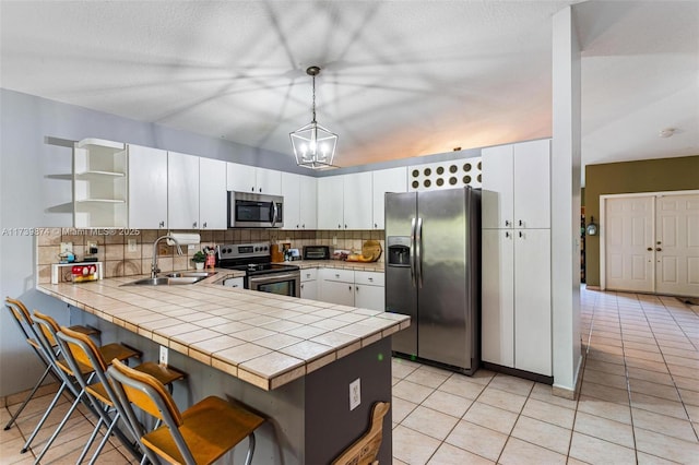 kitchen featuring sink, pendant lighting, stainless steel appliances, and kitchen peninsula