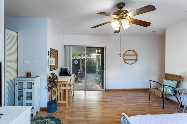 interior space featuring ceiling fan, light hardwood / wood-style flooring, access to exterior, and a textured ceiling