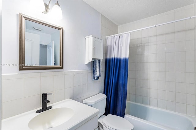 full bathroom featuring shower / bathtub combination with curtain, toilet, tile walls, a textured ceiling, and vanity