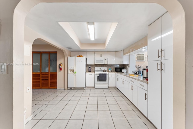 kitchen featuring white cabinetry, white appliances, a tray ceiling, and decorative backsplash