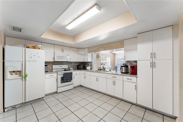 kitchen featuring sink, white appliances, tasteful backsplash, white cabinets, and a raised ceiling