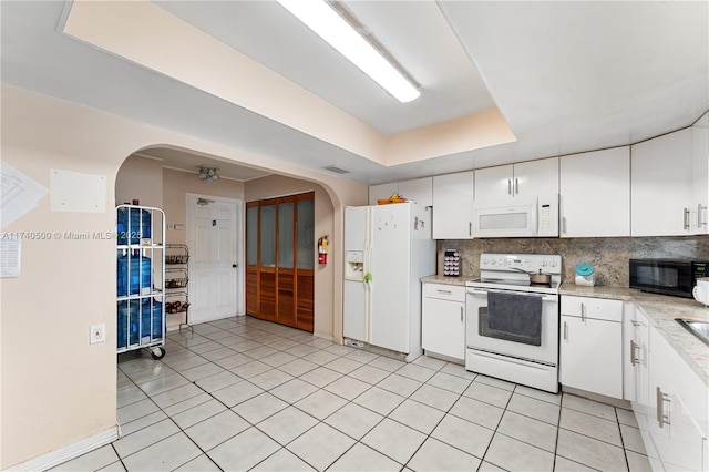 kitchen featuring a raised ceiling, white cabinetry, tasteful backsplash, and white appliances