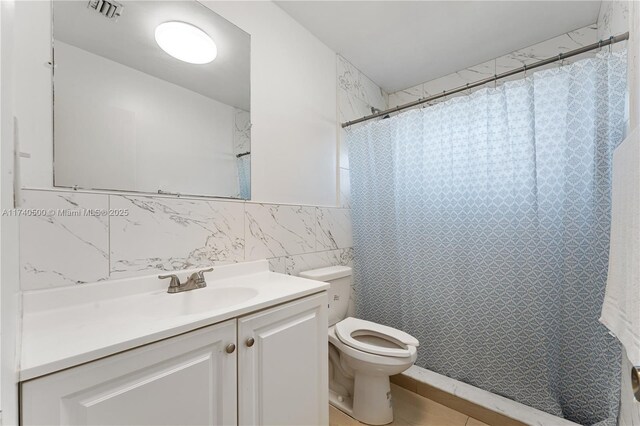 bathroom featuring vanity, curtained shower, tile walls, and toilet