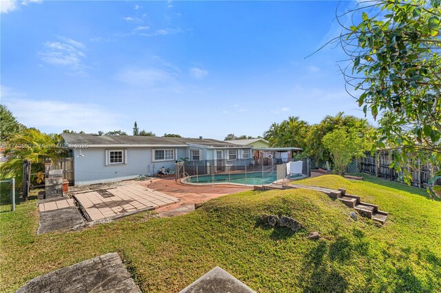 rear view of house featuring a fenced in pool, a lawn, and a patio area