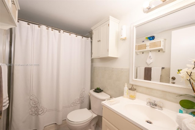 bathroom with vanity, toilet, and tile walls