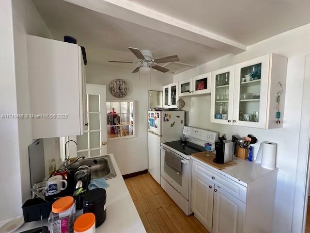 kitchen featuring sink, white appliances, light hardwood / wood-style flooring, ceiling fan, and white cabinets