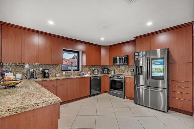 kitchen with appliances with stainless steel finishes, sink, backsplash, light tile patterned floors, and light stone countertops