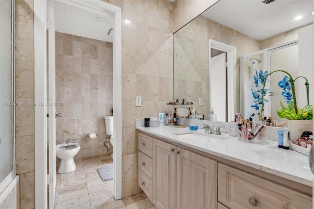 bathroom featuring a shower with door, a bidet, tile walls, and vanity