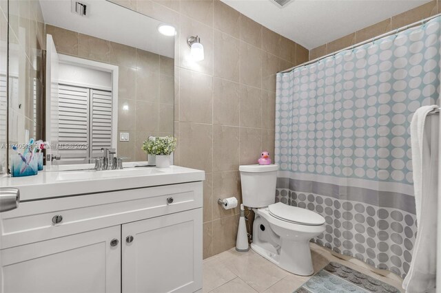 bathroom featuring tile walls, tile patterned flooring, vanity, toilet, and a shower with curtain