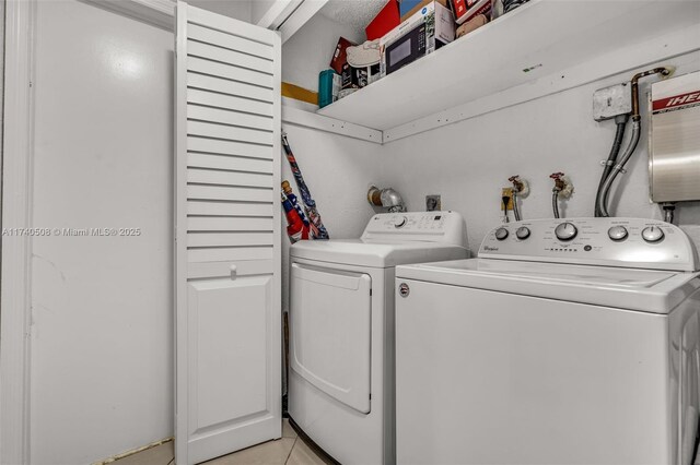 laundry room featuring washing machine and clothes dryer and light tile patterned floors