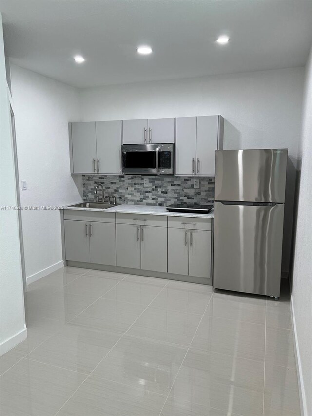 kitchen featuring sink, light tile patterned floors, appliances with stainless steel finishes, gray cabinets, and decorative backsplash