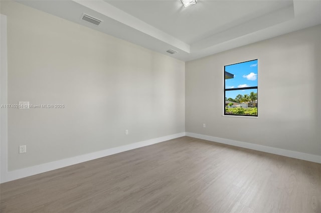 spare room featuring hardwood / wood-style floors and a tray ceiling