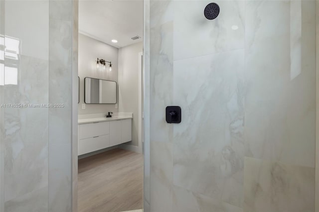 bathroom featuring vanity, wood-type flooring, and tiled shower