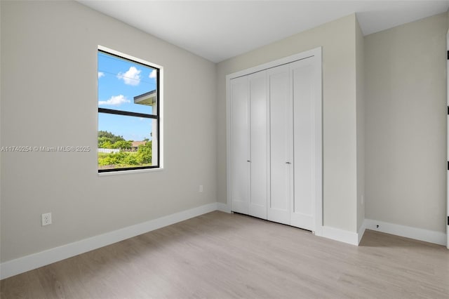 unfurnished bedroom featuring light hardwood / wood-style flooring and a closet