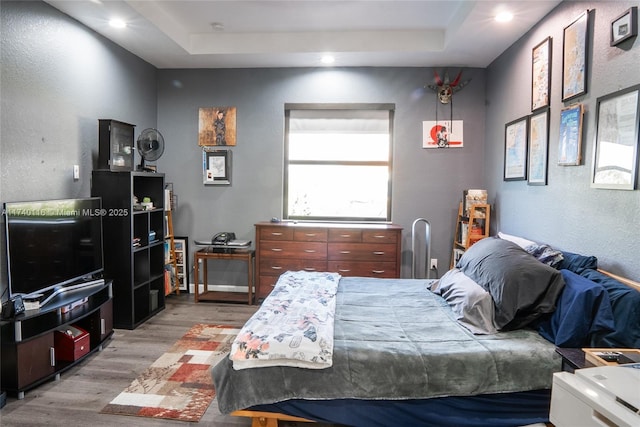 bedroom featuring hardwood / wood-style flooring and a raised ceiling