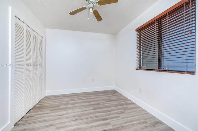 unfurnished bedroom featuring ceiling fan, a textured ceiling, light hardwood / wood-style floors, and a closet