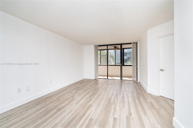 unfurnished room featuring floor to ceiling windows, a textured ceiling, and light wood-type flooring