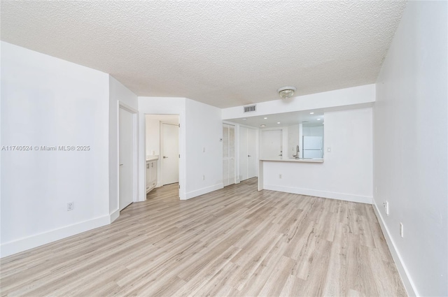 unfurnished living room with light hardwood / wood-style floors and a textured ceiling