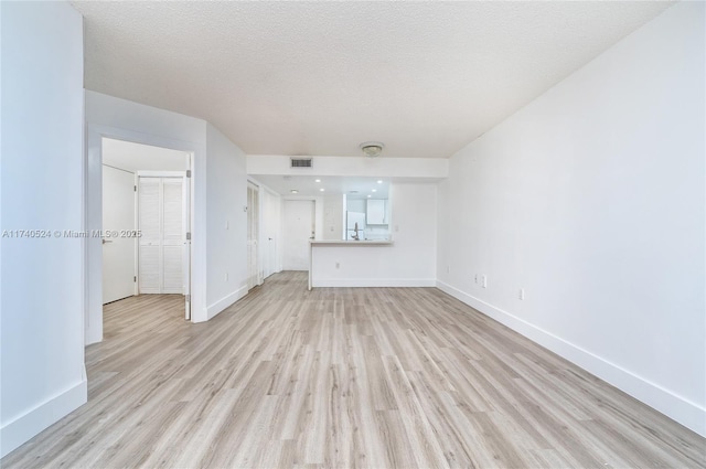 unfurnished living room with a textured ceiling and light wood-type flooring