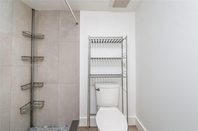 bathroom featuring tiled shower and toilet