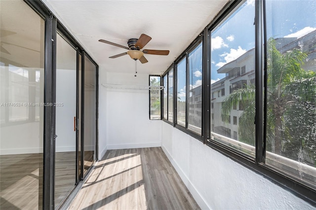 unfurnished sunroom with ceiling fan